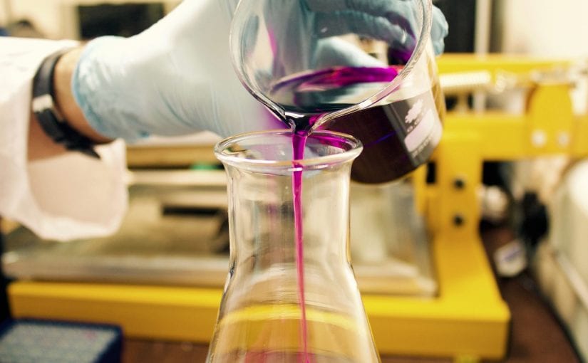 lab scientist pouring purple liquid